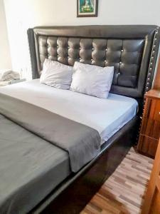 阿布贾Gifted Apartment & Residence的一张带皮革床头板和两个枕头的大床