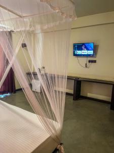 锡吉里亚Lankapura Heritage的一间卧室配有一张带窗帘的床和一台电视
