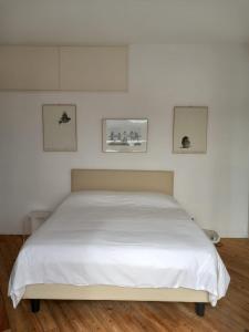 费拉约港Monolocale La Darsena的卧室内的一张床铺,墙上有三幅画