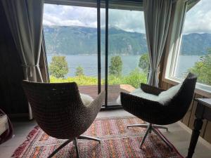 ØksendalsøraCabin by the Fjord的两把椅子坐在大窗户前