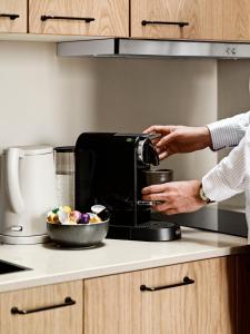 奥胡斯Aura Apartment Hotel的一个人在厨房里使用咖啡壶