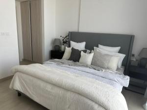 沙迦Modern Sanctuary W/ Pool & Gym access的卧室配有一张带白色床单和枕头的大床。
