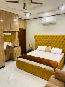 伊斯兰堡Britannia House near Islamabad International Airport and Motorway的一间卧室配有一张带黄色床头板的大床