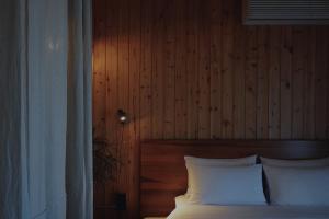 济州市At corner resort & garden的一间卧室配有一张带白色枕头的床和木墙