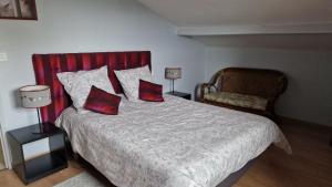 纳雅克Gite La Baraque的一间卧室配有一张带两个红色枕头和椅子的床