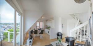 格罗森布罗德Hafenloft Großenbrode的白色的房间设有楼梯和一个带椅子的客厅