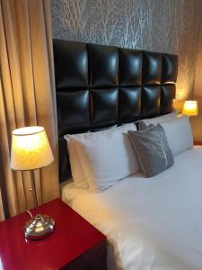 卡迪夫加的夫皇家酒店的一张带黑色床头板和台灯的床