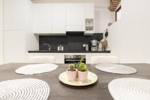 萨罗C-Apartment Lake Garda的厨房配有白色橱柜和盆栽桌子
