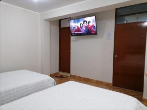 LambayequeHostal Tulipán Rojo的一间卧室配有两张床和一台平面电视