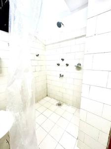 科尔瓦Luxurious 1BHK with a Pool AniRah Homes in Colva的浴室内铺有白色瓷砖并配有淋浴帘的淋浴间
