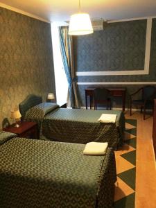 科森扎Hotel Excelsior的酒店客房带两张床和一张桌子以及椅子。