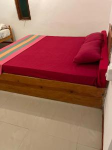 阿鲁甘湾Crystal Bay的一张铺有红色床单和红色枕头的木床