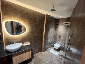 戈勒克布尔Ashoka Hotel的一间带水槽、镜子和淋浴的浴室