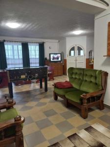 SajókápolnaEvita Vendégház的客厅配有绿色沙发和钢琴