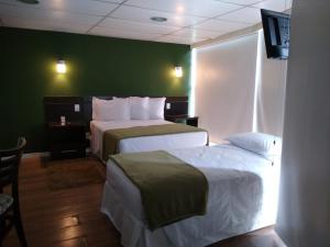 马瑙斯Uiara Amazon Resort的酒店客房设有两张床和绿色的墙壁。