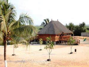 Abomey-CalaviASSOUKA Eco-Village du lac Nokoué的一座带茅草屋顶和棕榈树的大型木质建筑