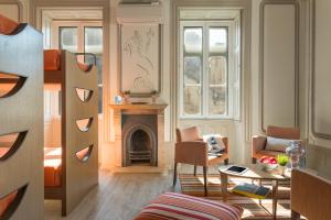 科英布拉Serenata Hotel & Hostel Coimbra的客厅设有壁炉、桌子和椅子