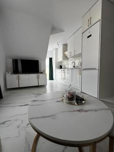 蒂米什瓦拉Gold Tag Apartament的白色的厨房配有桌子和白色冰箱