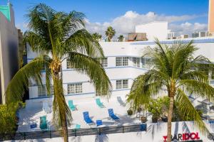 迈阿密海滩Best location in SOBE - 2 min to beach & Ocean Dr的白色的建筑,设有蓝色的椅子和棕榈树