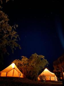 El SargentoGlamping 3 Idiomas的两个白色帐篷在晚上点燃