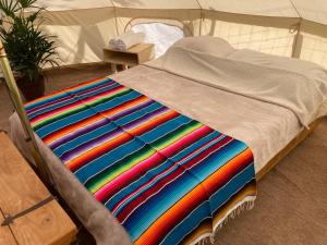 El SargentoGlamping 3 Idiomas的帐篷内的床上的彩色毯子