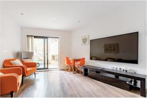 KentChic DuoRooms with Modern Comfort for Families的客厅配有橙色椅子和大屏幕平面电视。