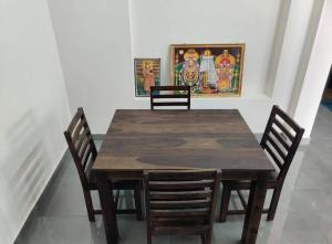 蒂鲁瓦纳马莱Wind Chimes的一张带四把椅子的木桌和墙上的一幅画