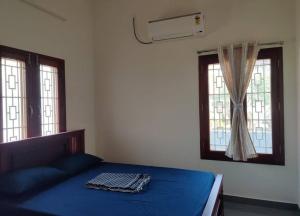 蒂鲁瓦纳马莱Wind Chimes的一间卧室设有蓝色的床和2个窗户。