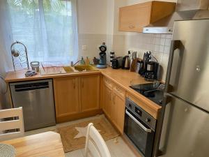 圣丹尼斯F2 St Denis Jardin d'état的厨房配有木制橱柜和不锈钢冰箱。