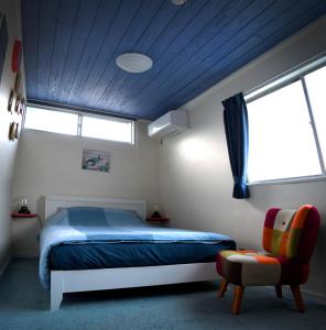 下田Ramjet Sotoura Beach House Shimoda的一间卧室设有一张床、一个窗口和一把椅子