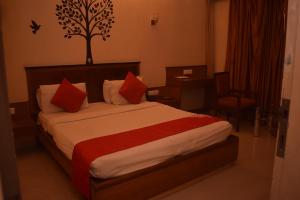 塞恩HOTEL DHIRAJ的配有红色枕头的床的酒店客房
