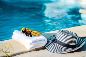 内坦亚Boutique Villa with Rooftop Pool的坐在游泳池旁的帽子和太阳镜