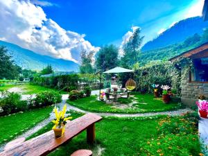 马拉里Hotel Himalayan Classic, Manali的草地上带长凳和桌子的花园