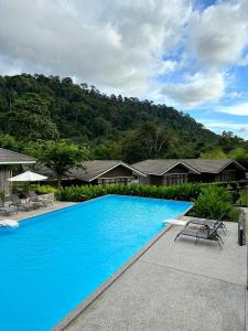 瓜埠Rebungan Resort Langkawi的一个带椅子和房屋的大型蓝色游泳池