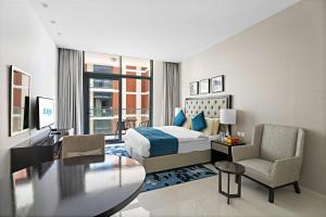 迪拜Aliving Elite Studio Celestia A Dubai South的配有一张床、一张桌子和一张桌子的酒店客房