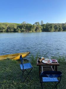 Ban Lam PiSawasdee Lagoon Camping Resort的一张桌子和两把椅子以及一条船上的湖水