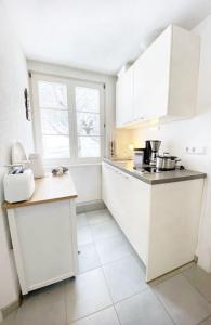 福尔巴赫Apartment Rose的厨房配有白色橱柜和白色瓷砖地板。