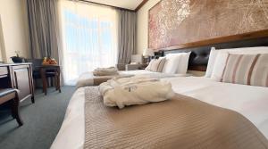 班斯科Platinum Hotel and Casino Bansko的酒店客房,配有两张带白色床单的床