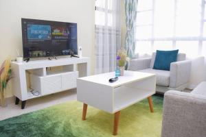MeruMarvel Homes的客厅配有电视和白色咖啡桌。