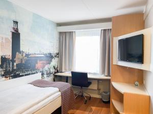 斯德哥尔摩Good Morning+ Hägersten的一间卧室配有一张床、一张书桌和一台电视。