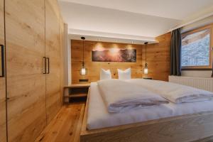 阿亨基希loisi's Boutiquehotel的卧室配有一张白色大床和木墙