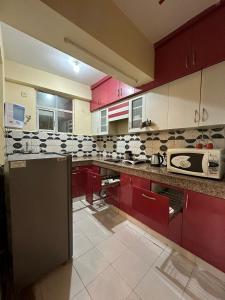 加济阿巴德Royal Ambience的一间厨房,配有红色橱柜和台面