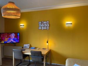 斯海弗宁恩Plato by Hofstad Studio’s的一间设有桌子的用餐室和一台黄色墙壁上的电视