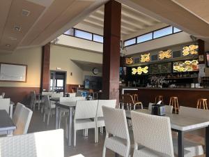 MendexaCamping & Bungalows Leagi的一间设有白色桌椅的餐厅和一间酒吧