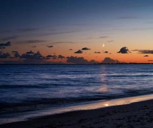 KinarDoga Resort - דוגה ריזורט的日落在海滩上,月亮在天空中