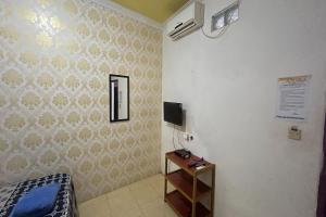 MamujuOYO 93416 Wisma Alam Syariah的一间卧室配有一张床,墙上配有电视