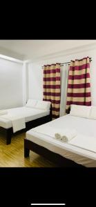 BurgosVilla Malinao Oceanview Resort - Deluxe bungalow的配有条纹窗帘的客房内的两张床