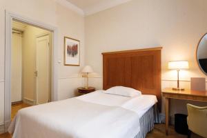 马尔默瑞典精英酒店的卧室配有白色的床、书桌和灯