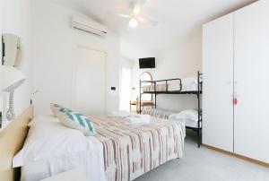 里米尼Albergo Villa Denny的白色卧室,配有带条纹毯子的床