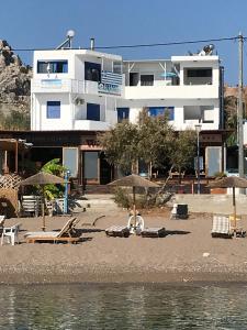 阿彻奇洛斯Riva Del Mare的海滩上的一座建筑,配有椅子和遮阳伞